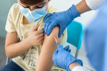 Nurse Injecting Covid-19 Vaccine at Boy In Arm For Virus Protection In Clinic.