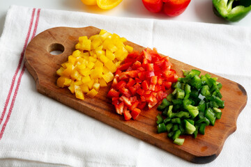 Chopped Fresh Colored Peppers on a Rustic Wooden Board, side view..