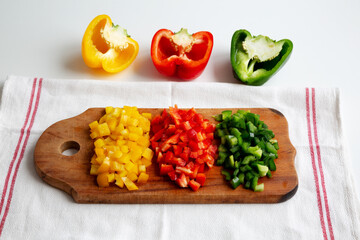 Chopped Fresh Colored Peppers on a Rustic Wooden Board, side view..