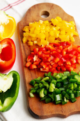 Chopped Fresh Colored Peppers on a Rustic Wooden Board, side view. Close-up.