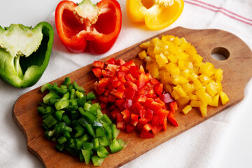Chopped Fresh Colored Peppers on a Rustic Wooden Board, side view.
