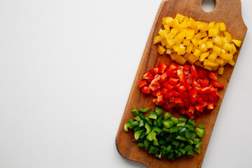 Chopped Fresh Colored Peppers on a Rustic Wooden Board, top view. Flat lay, overhead, from above. Space for text.