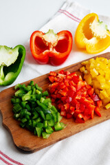 Chopped Fresh Colored Peppers on a Rustic Wooden Board, low angle view.