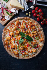 Fresh baked pizza with ingredients on a dark stone table .
