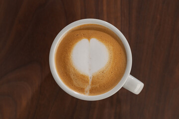Fototapeta premium Flat white in white cup with simple latte art on walnut wood table