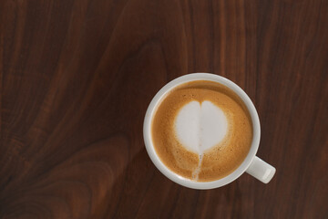Flat white in white cup with simple latte art on walnut wood table