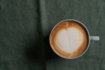 Flat white in white cup with simple latte art on turquoise napkin
