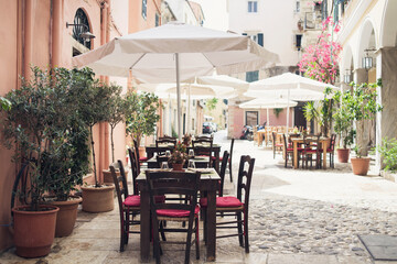 Fototapeta na wymiar Corfu town beautiful street with cafe tables and flowers, Corfu island, Ionian islands, Greece. Picturesque landmark of Kerkyra old town