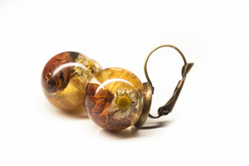 Handmade jewelry closeup. Natural organic dried flowers preserved in epoxy resin sphere balls on...