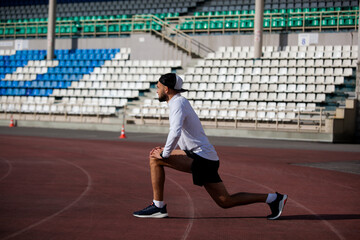 Man stretches the body before running on race track in stadium