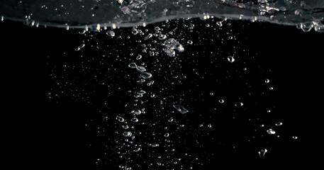 Soda water bubbles splashing and floating drop in black background represent sparkling and...