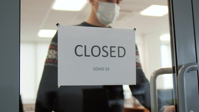 Funny man in medical mask removing banner with Closed on door