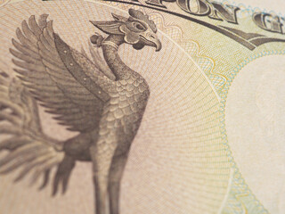 Fragment of 10,000 yen Japanese banknote. Background with Phoenix bird and copy space to its right. Backdrop about money, bookkeeping and the economy of Japan. Macro