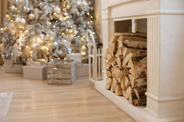 wood logs in fireplace with christmas tree as background - cozy luxury chalet lodge home interior. wood in fireplace on christmas holiday season cozy interior background