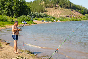 a fat man a fisherman in swimming trunks on the river bank will probably throw a fishing rod for fish