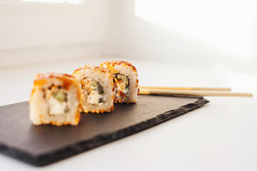 Sushi japan food on black plate at sushi restaurant or takeout with chopsticks on white. Delicious sushi japanese food with chopsticks fresh at the restaurant or takeout delivery.