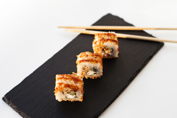 Sushi japan food on black plate at sushi restaurant or takeout with chopsticks on white. Delicious sushi japanese food with chopsticks fresh at the restaurant or takeout delivery.
