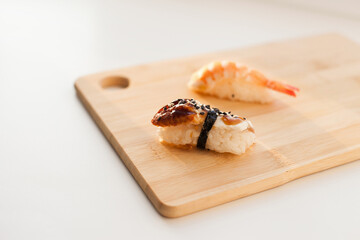 Sushi delivery and takeout - Nigiri and unagi sushi japanese food on wooden board isolated on white. Nigiri unagi sushi and chopsticks japanese food on wooden board close up.