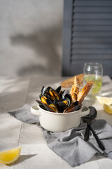Cooked, boiled mussels with lemon juice, parsley and toasted bread in white bowl (plate) on the table. Seafood, copy space. 