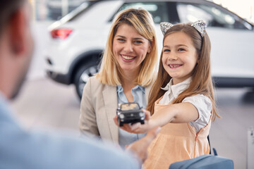 Happy family is having a good time at auto shop while searching for a new car to buy. Car, shop, buying