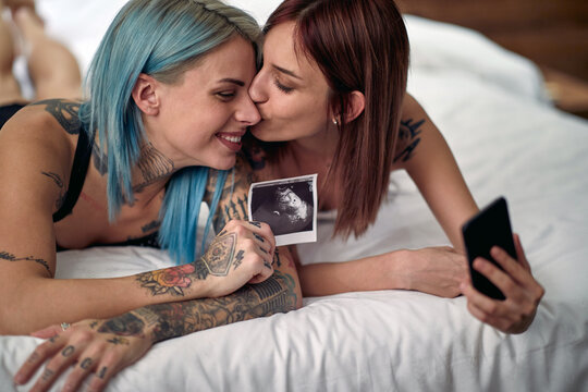 Joyful lesbian couple sharing hapiness of a pregnancy