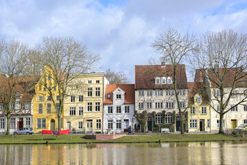 Beautiful historic house facades on the banks of the river Trave in the old town of the hanseatic city of Lubeck, Germany, blue sky with clouds on a sunny day in early spring, copy space