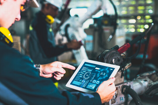 Factory workers working with adept robotic arm in a workshop . Industry robot programming software for automated manufacturing technology .