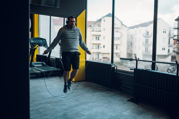 Middle aged man training in the gym with jump rope