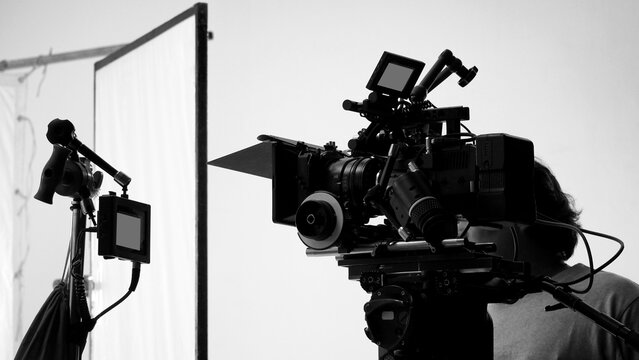 Movie shooting or video filming production by crew team and professional equipment such as super ultra high definition digital camera with tripod and lighting set in studio and black and white styles.