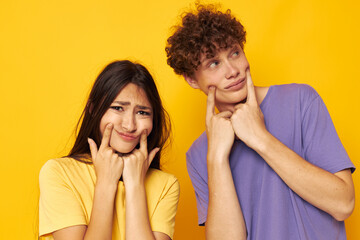Naklejka premium cute young couple casual clothes posing emotions antics yellow background unaltered
