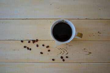 Black coffee in a cup and scattered coffee beans.