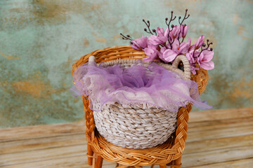 Shoot set up with flowers, basket for newborn on the wood chair. Photo zone for a photo session of...