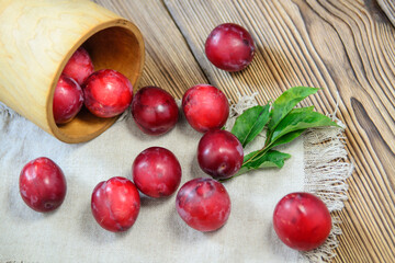 Large ripe plums spilled out of an overturned wicker basket onto a napkin on the table