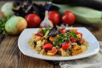 Stewed vegetables in a white bowl on wooden table