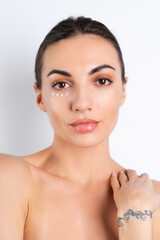 Close-up beauty portrait of a topless woman with perfect skin and natural make-up, with anti-aging cream dots to moisturize and firm the skin under the eyes.