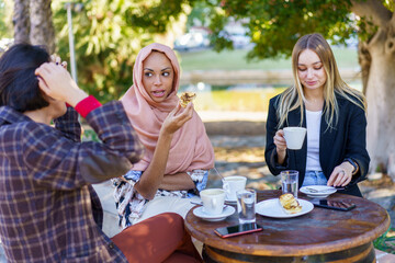 Multiracial women having coffee break on terrace of cafe