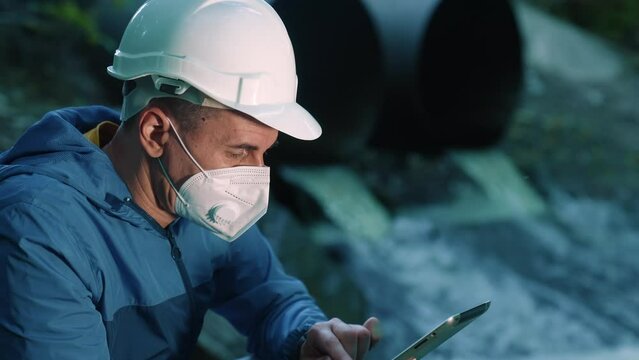 water treatment engineer examines environmental pollution. biologist with digital tablet examines water allergy. worker in helmet works environmental app sun pollution. biologist sewage test water