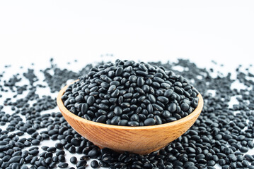 A bowl of small black beans on a white background