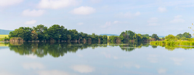 Summer landscape, panorama, with river and trees reflected in river water