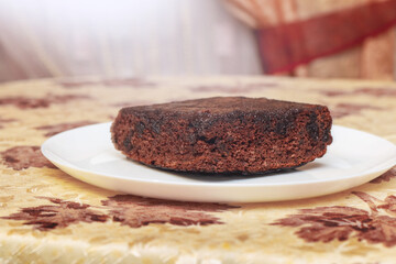 Piece of cake, biscuit in a plate on the table by the window