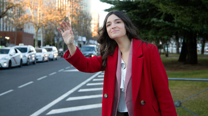 Hispanic woman raising her hand to order a taxi