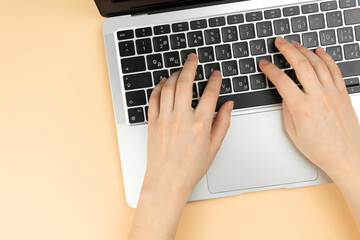 Female hands and laptop keyboard on a beige background. Concept workspace, work at the computer, freelance and design. Flat lay, top view and copy space photo