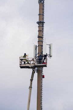 Monteure mit einem Steiger an einen Mobilfunkmast bei Wartungsarbeiten