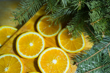 Fototapeta na wymiar Orange slices on a wooden board with fir branches