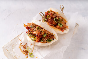 Asian fusion vegan white soft bao with fermented and fresh vegetables, spicy sauce and crunchy onion flakes