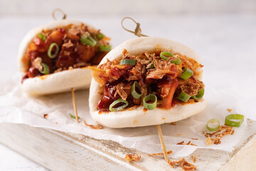 Asian fusion vegan white soft bao with fermented and fresh vegetables, spicy sauce and crunchy onion flakes