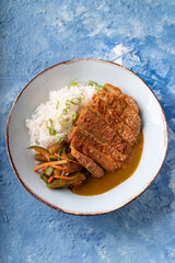 Asian fusion vegan meat-free chickpea steak, garnished with carrot, zucchini and white rice