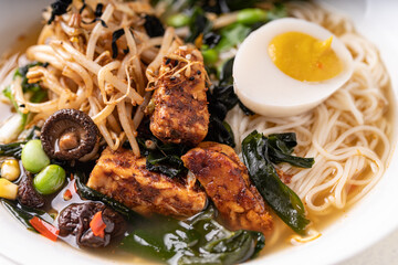 Asian fusion vegan meat-free ramen noodles with mushrooms, fermented tofu, sprout, beans, vegan egg and green pak choi leaves