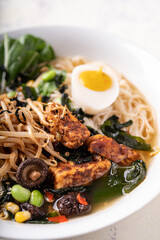 Asian fusion vegan meat-free ramen noodles with mushrooms, fermented tofu, sprout, beans, vegan egg and green pak choi leaves