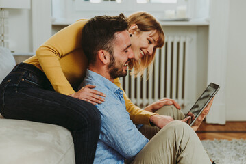 Young couple spending time together at home. Man and woman sitting on the couch and having fun....